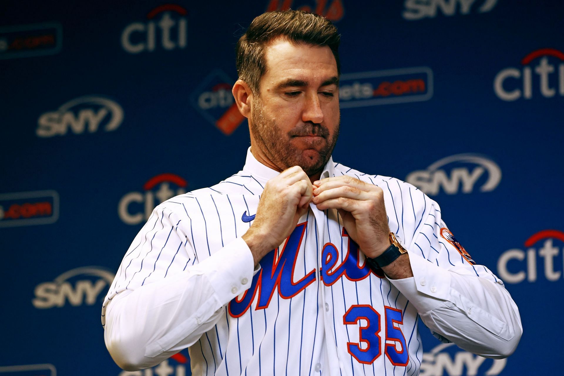 Justin Verlander of the New York Mets buttons up his new jersey before he is introduced during a press conference at Citi Field