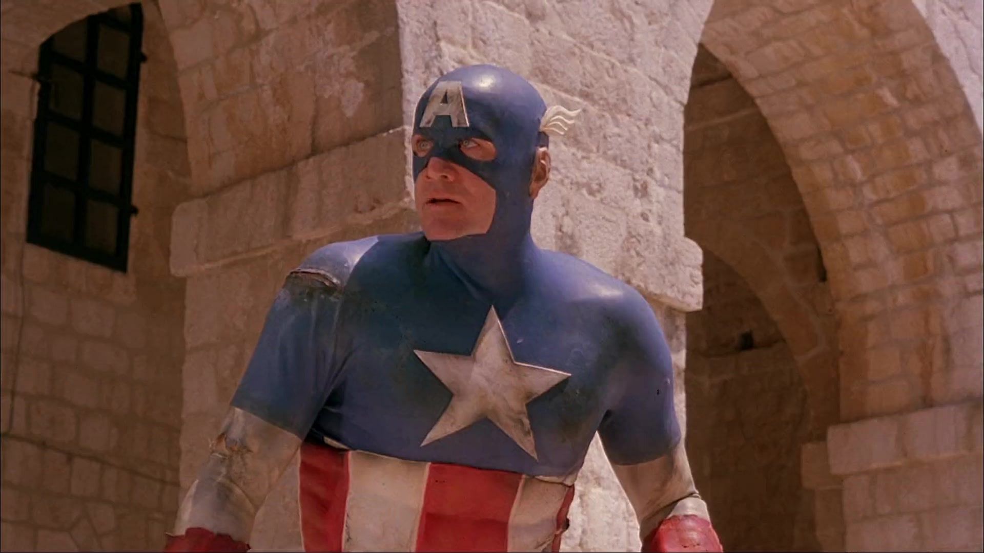 A laughable Captain America in a bright red and blue costume with fake muscles and a cowl helmet (Image via 21st Century Film Corporation)