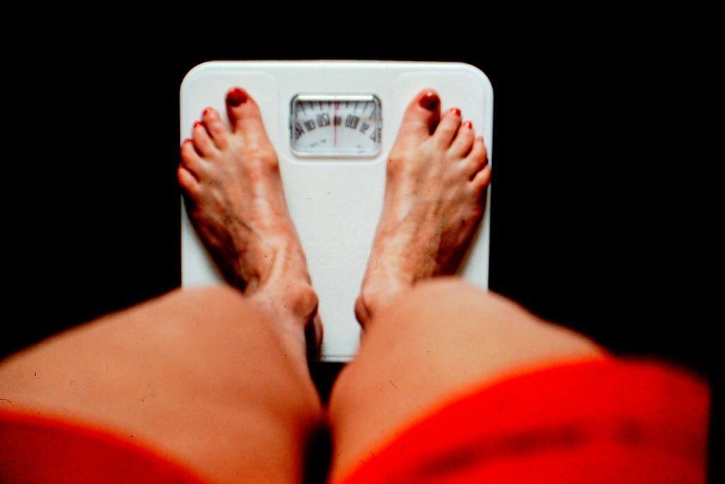 Woman standing on a scale(Image via Getty Images)