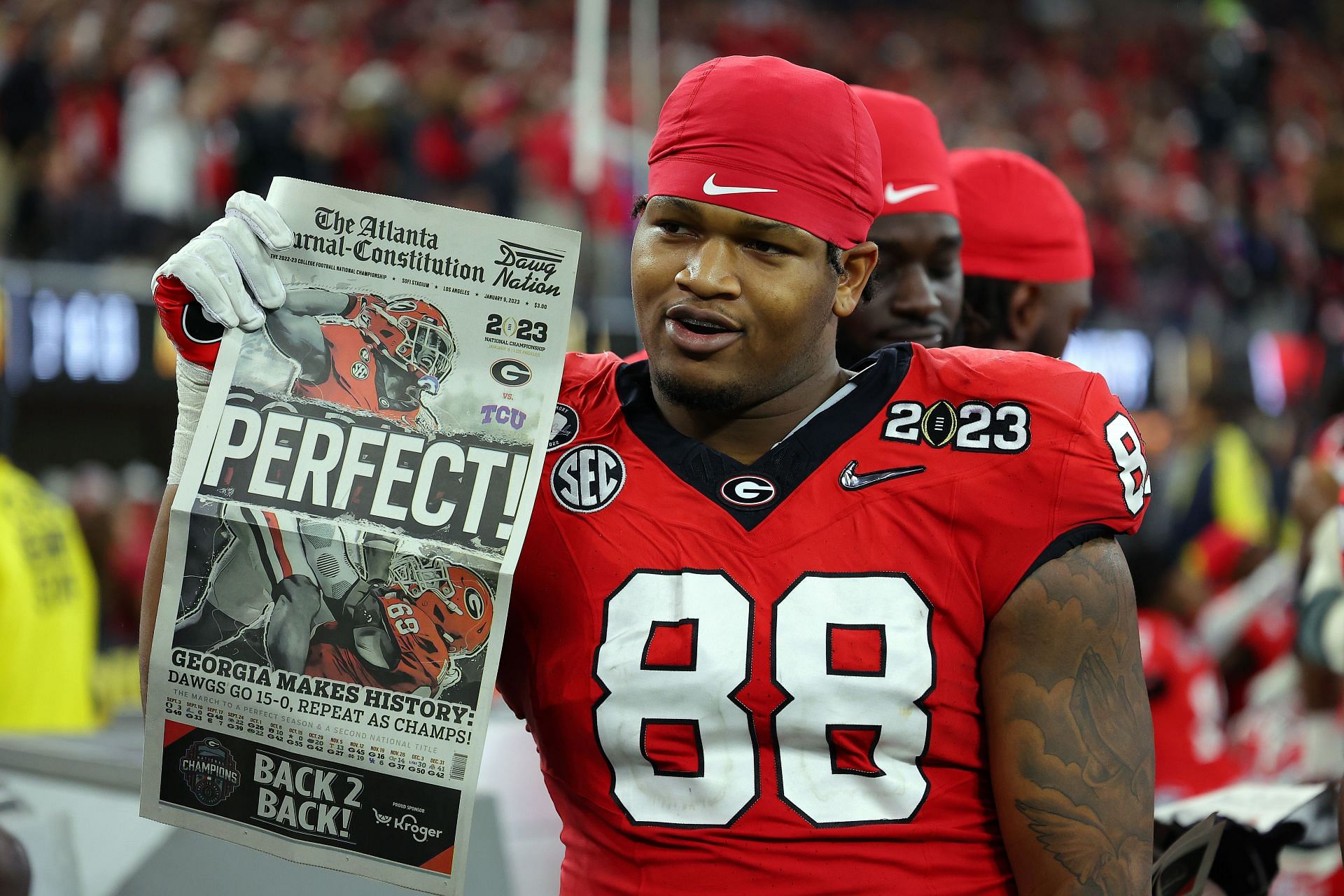 Jalen Carter #88 of the Georgia Bulldogs celebrates with a newspaper reading "Perfect!" after defeating the TCU Horned Frogs