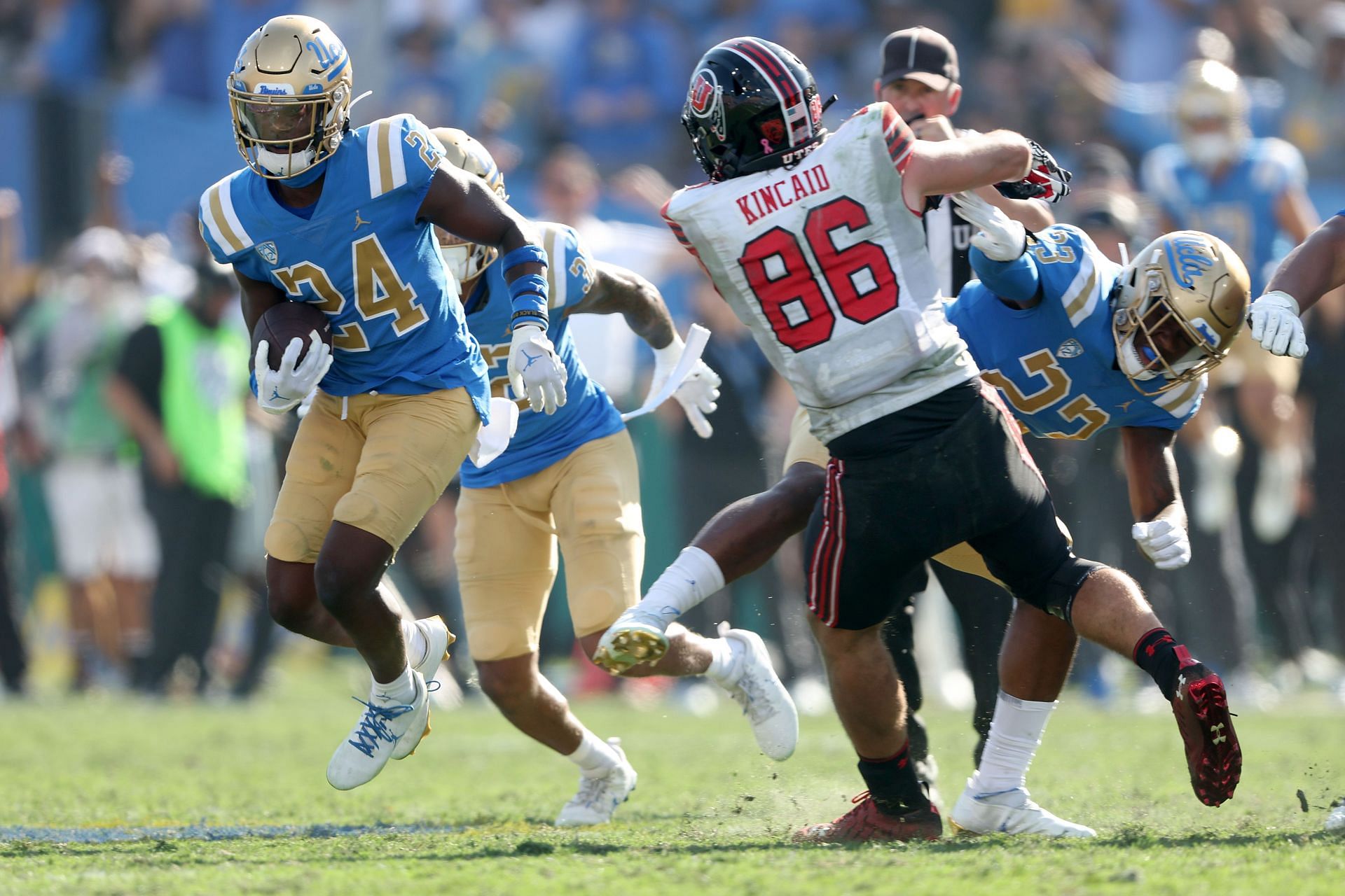 Jaylin Davies #24 of the UCLA Bruins eludes the tackle of Dalton Kincaid #86 of the Utah Utes