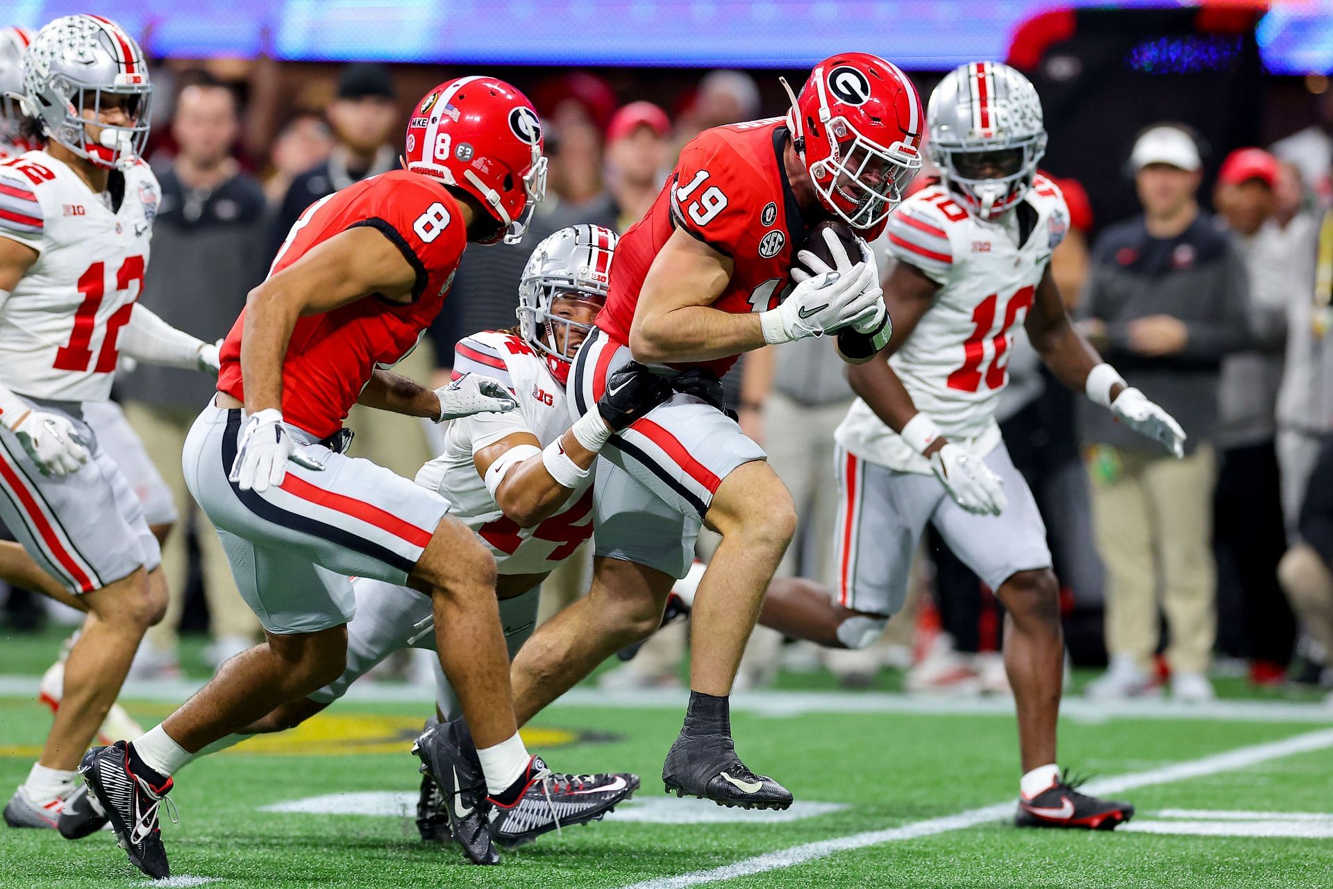 Brock Bowers #19 of the Georgia Bulldogs is tackled by Ronnie Hickman #14 of the Ohio State Buckeyes