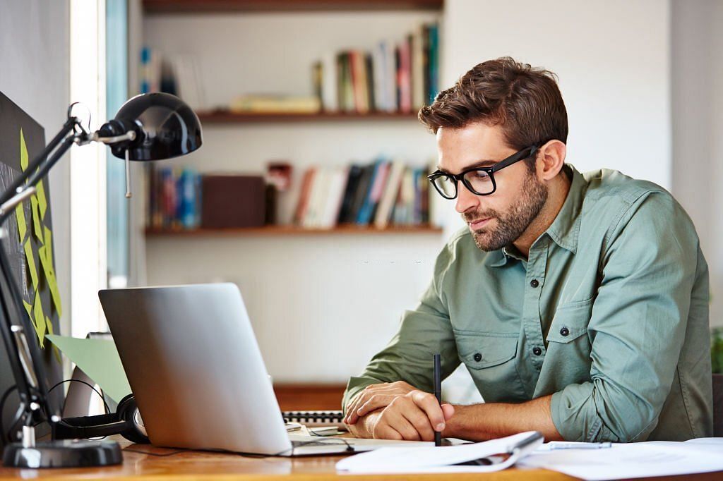 Shot of a young man sitting at a table at home working on a laptop