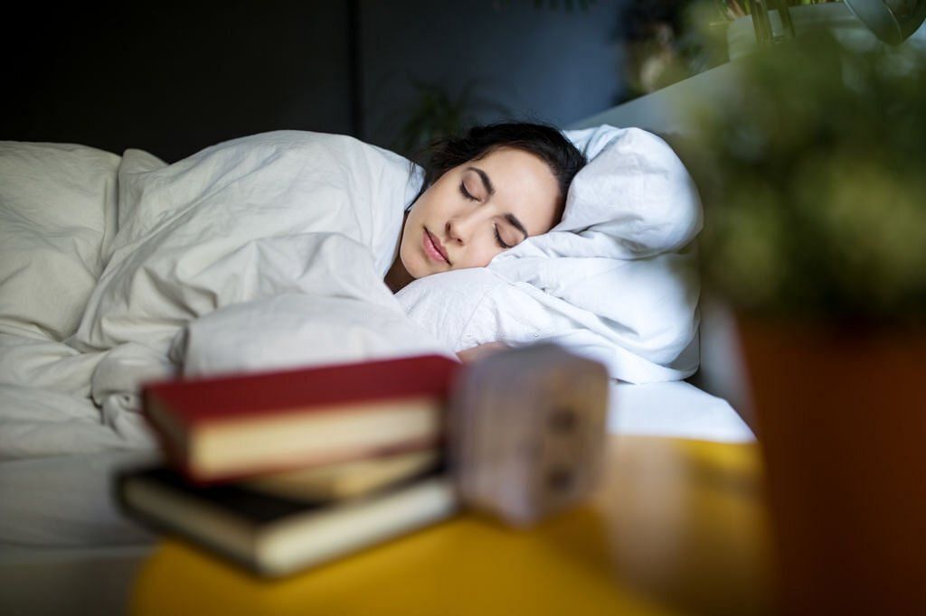 Young woman sleeping peacefully on her bed at home (Image via Getty Images)