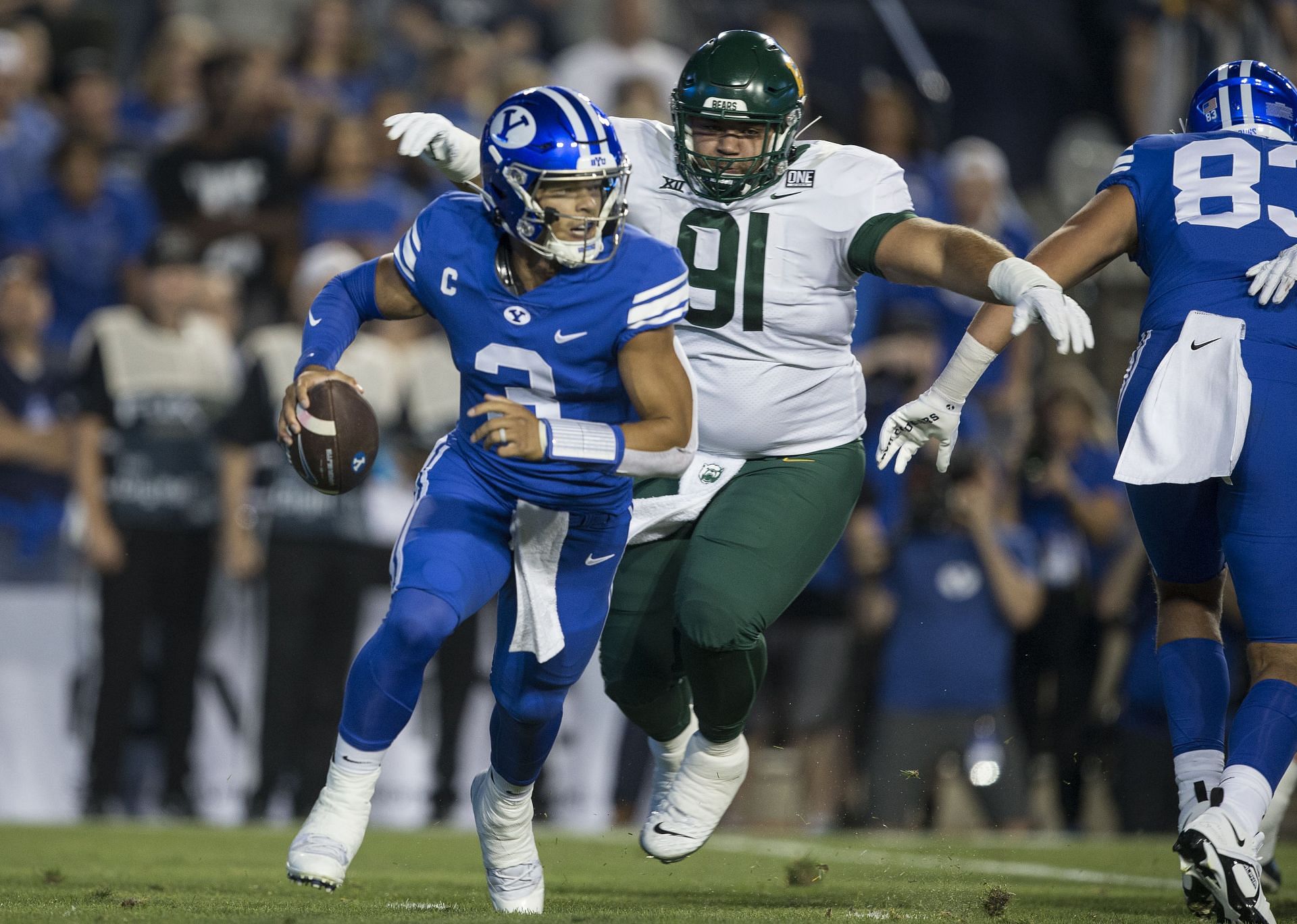 Jaren Hall #3 of the Brigham Young Cougars is chased out of the pocket by Jaxon Player #91 of the Baylor Bears