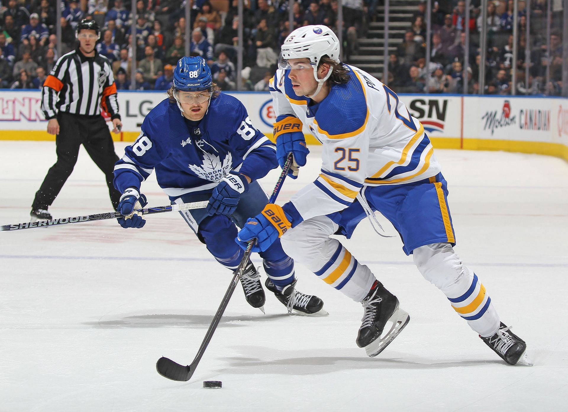 Owen Power #25 of the Buffalo Sabres skates with the puck against William Nylander #88 of the Toronto Maple Leafs