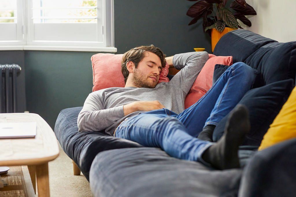 Young white man with beard asleep on sofa