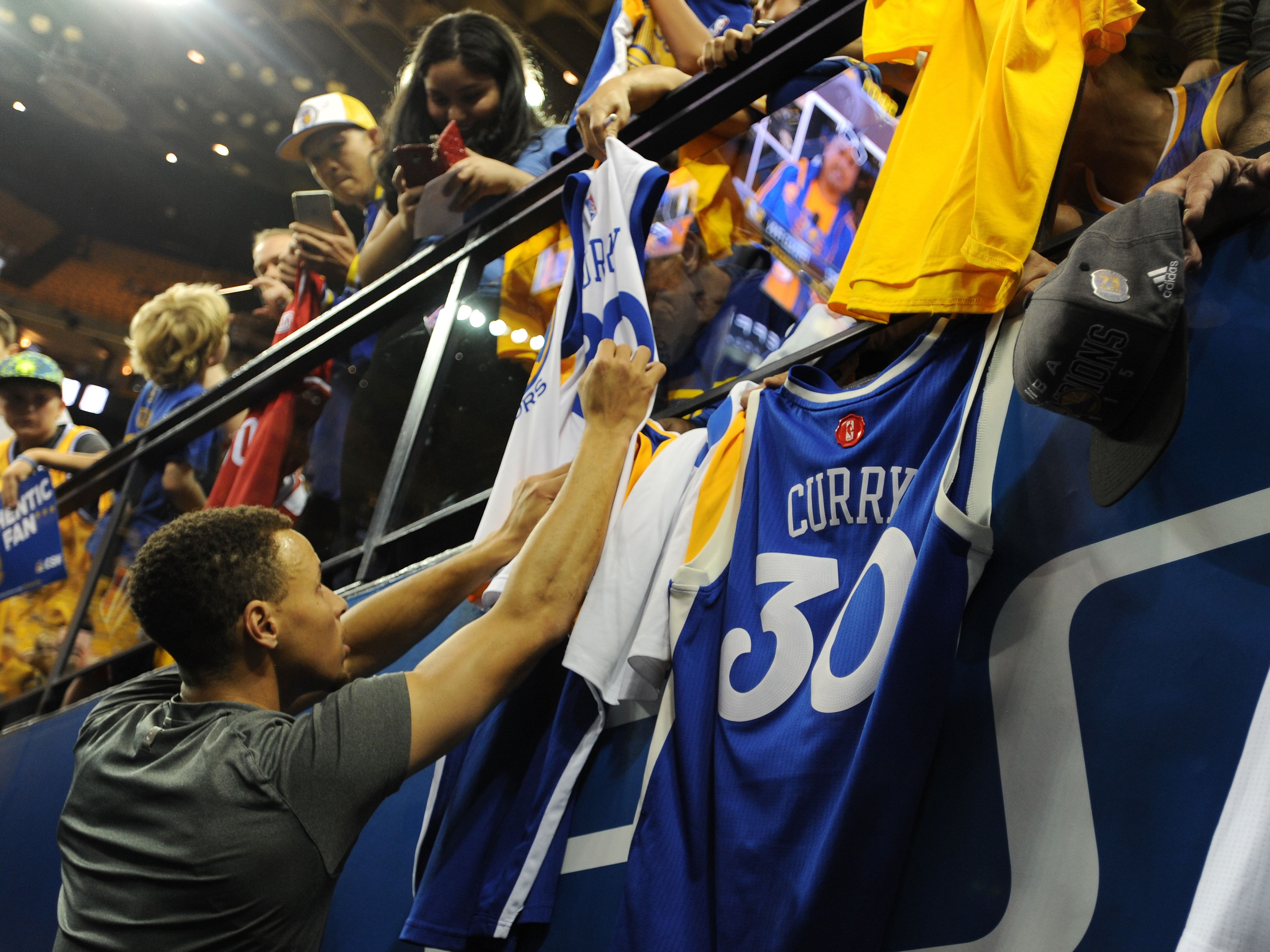 Steph Curry signing jerseys before an NBA game.