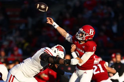 Wisconsin Badgers nose tackle Keeanu Benton #95 pressures Rutgers Scarlet Knights quarterback Noah Vedral #0 who throws a pass for an interception returned for a touchdown 