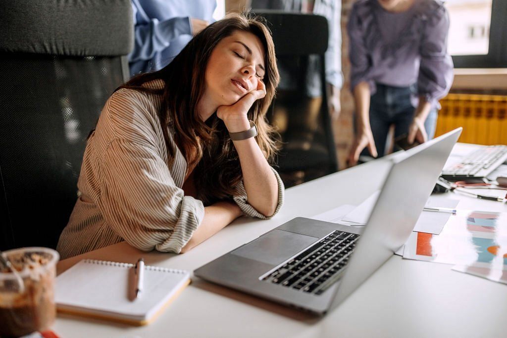 Young tired businesswoman sleeping at the office desk