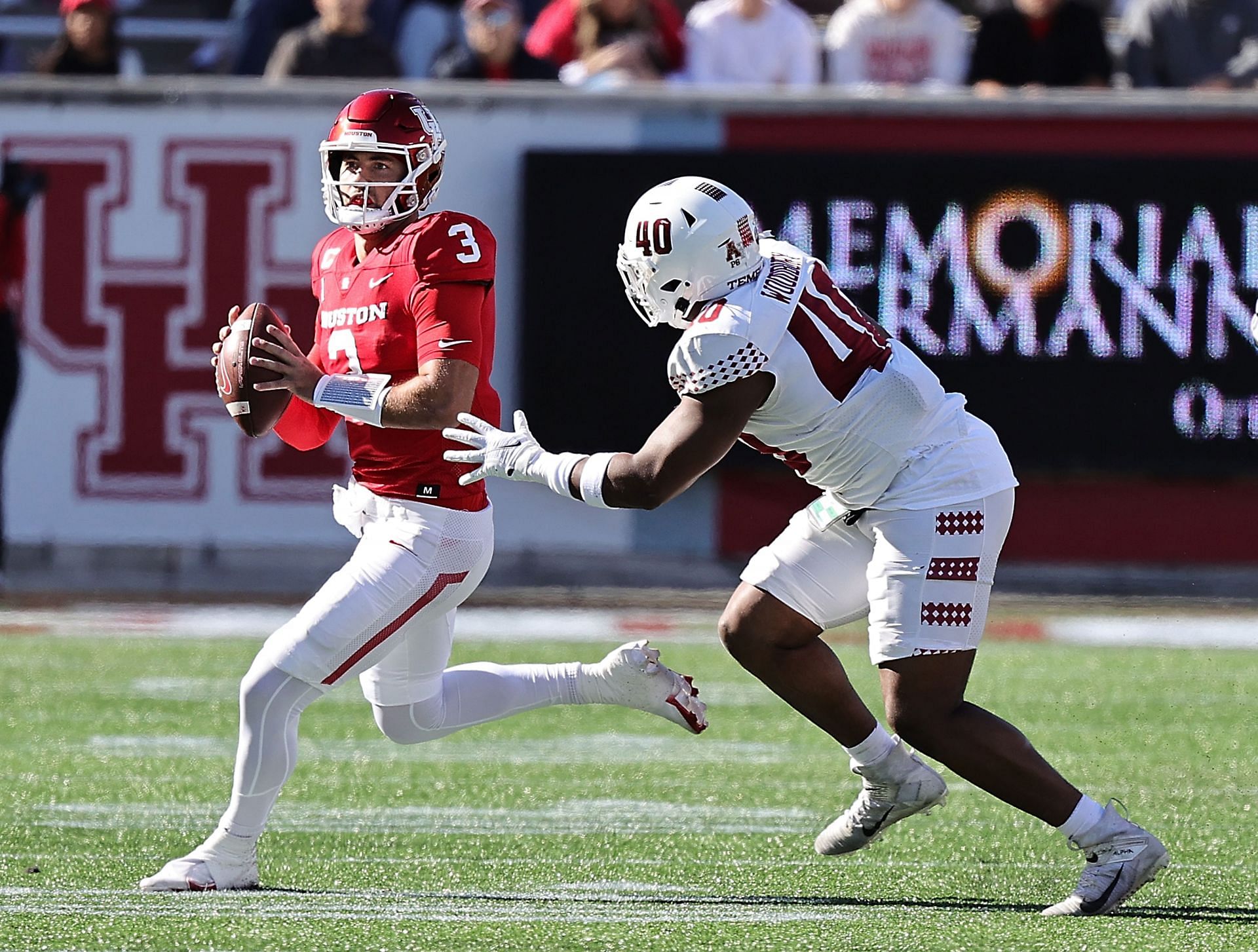 Clayton Tune #3 of the Houston Cougars runs out of the pocket as he is pressuredc wby D.J. Woodbury #40 of the Temple Owls 