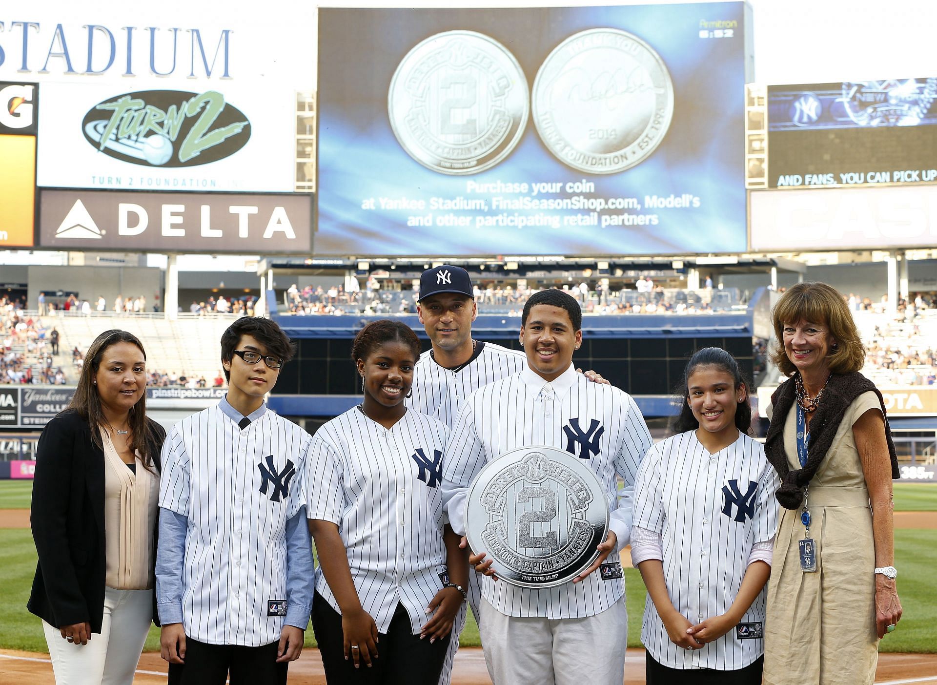 Tampa Bay Rays v New York Yankees NEW YORK, NY - JULY 01: Derek Jeter #2 of the New York Yankees stands with members of his Turn 2 Foundation and their commemorative coin launch before the start of a game against the Tampa Bay Rays at Yankee Stadium on July 1, 2014 in the Bronx borough of New York City. (Photo by Rich Schultz/Getty Images)