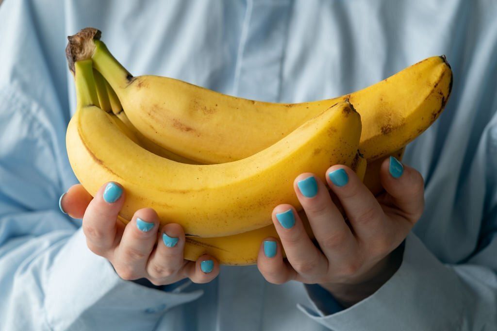 Ripe yellow bananas in the hands of a woman, bought at a shopping market