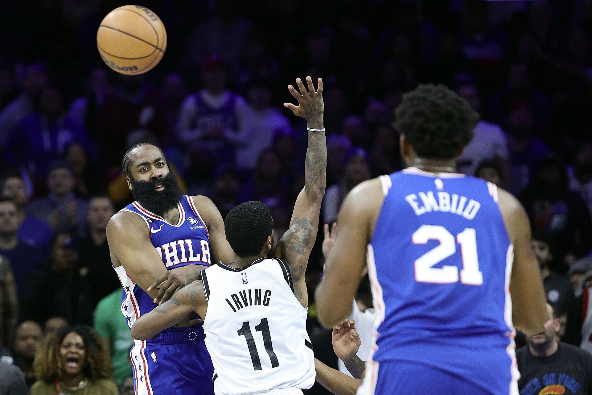 James Harden blocking Kyrie Irving while making a shot Joel Embiid in the frame