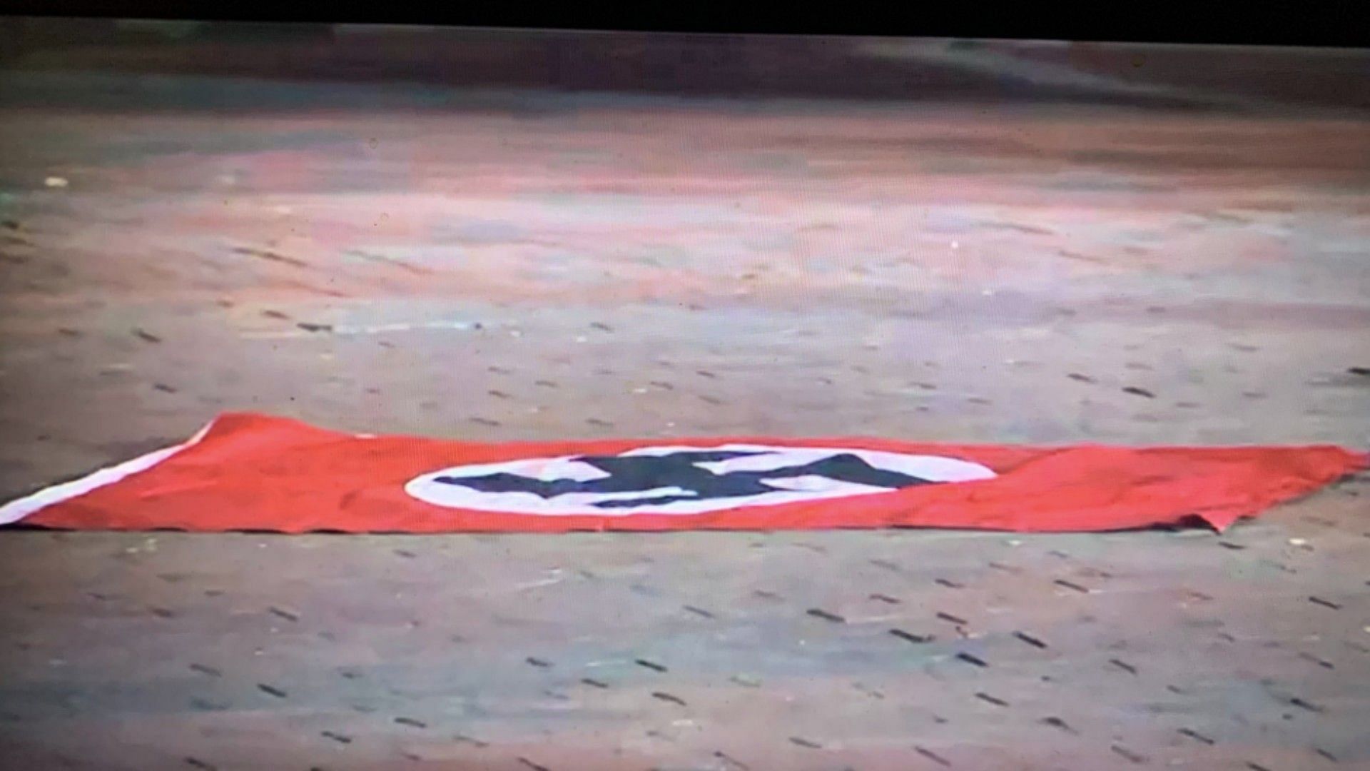 The Nazi flag waved by the suspect pictured on the ground (Image via Melanie Alnwick/Twitter)