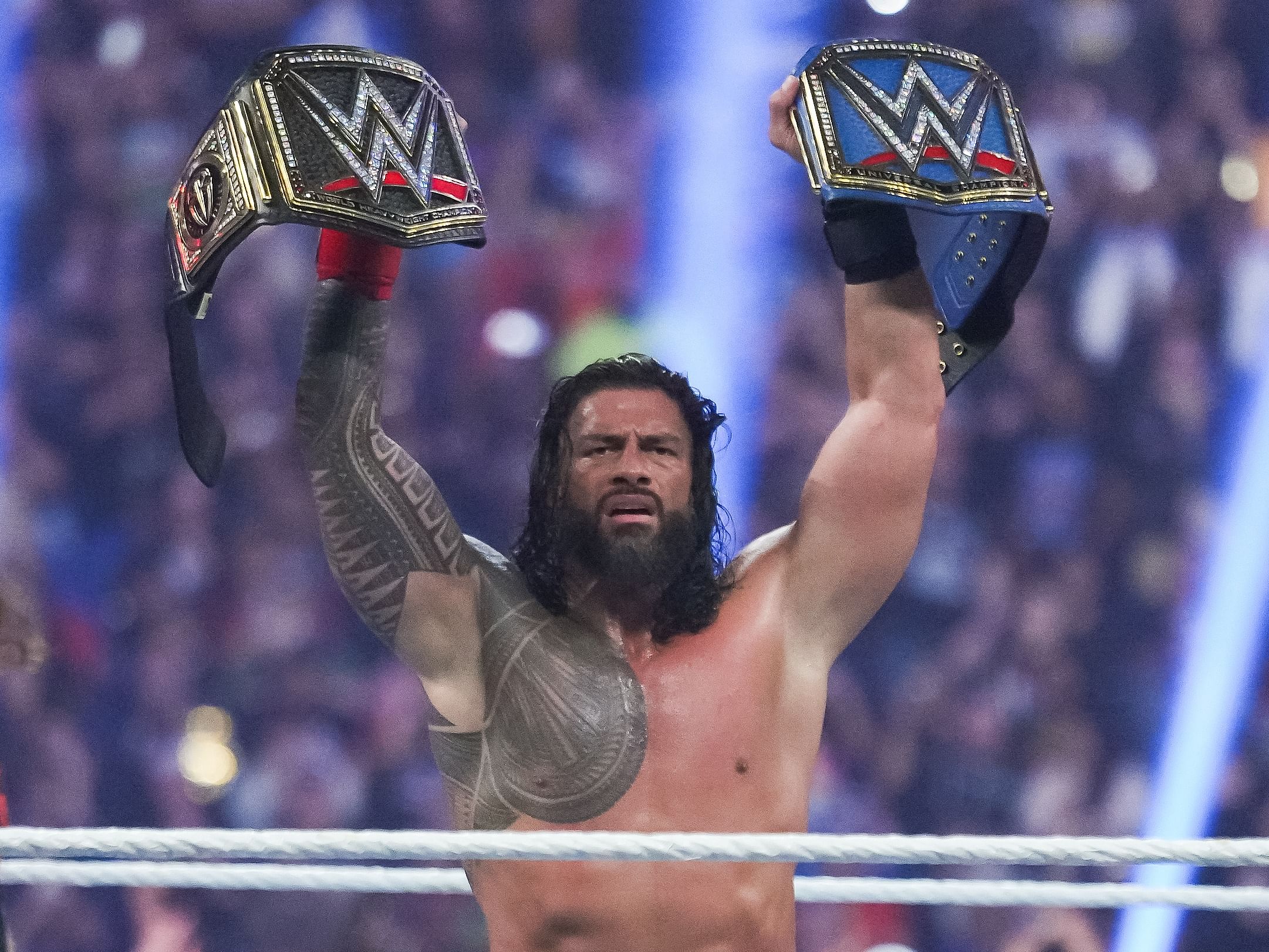 Roman Reigns holding the WWE and Universal Championships.