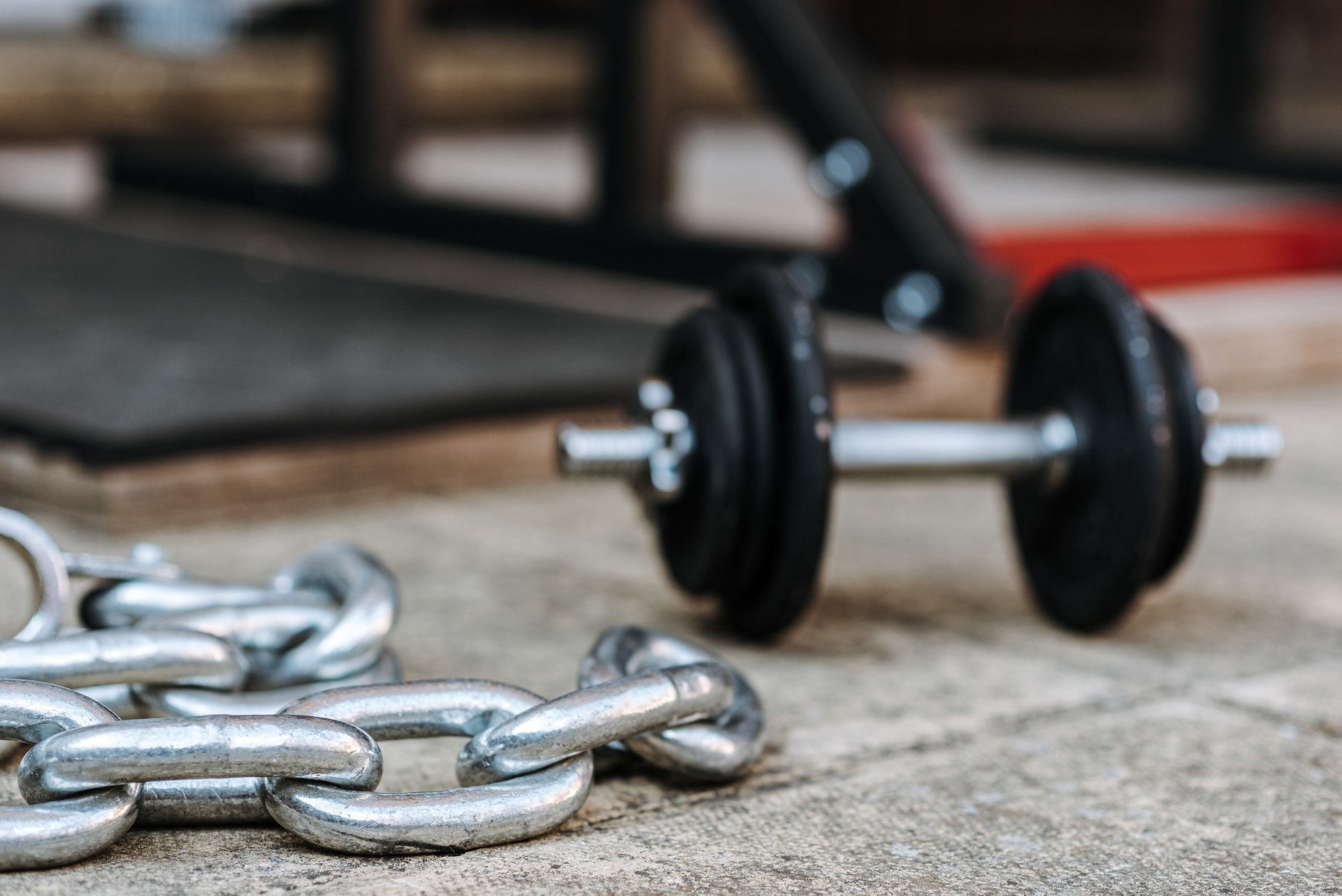Floor chest press can be done using chains at the end of a barbell. (Photo via Pexels/Anete Lusina)