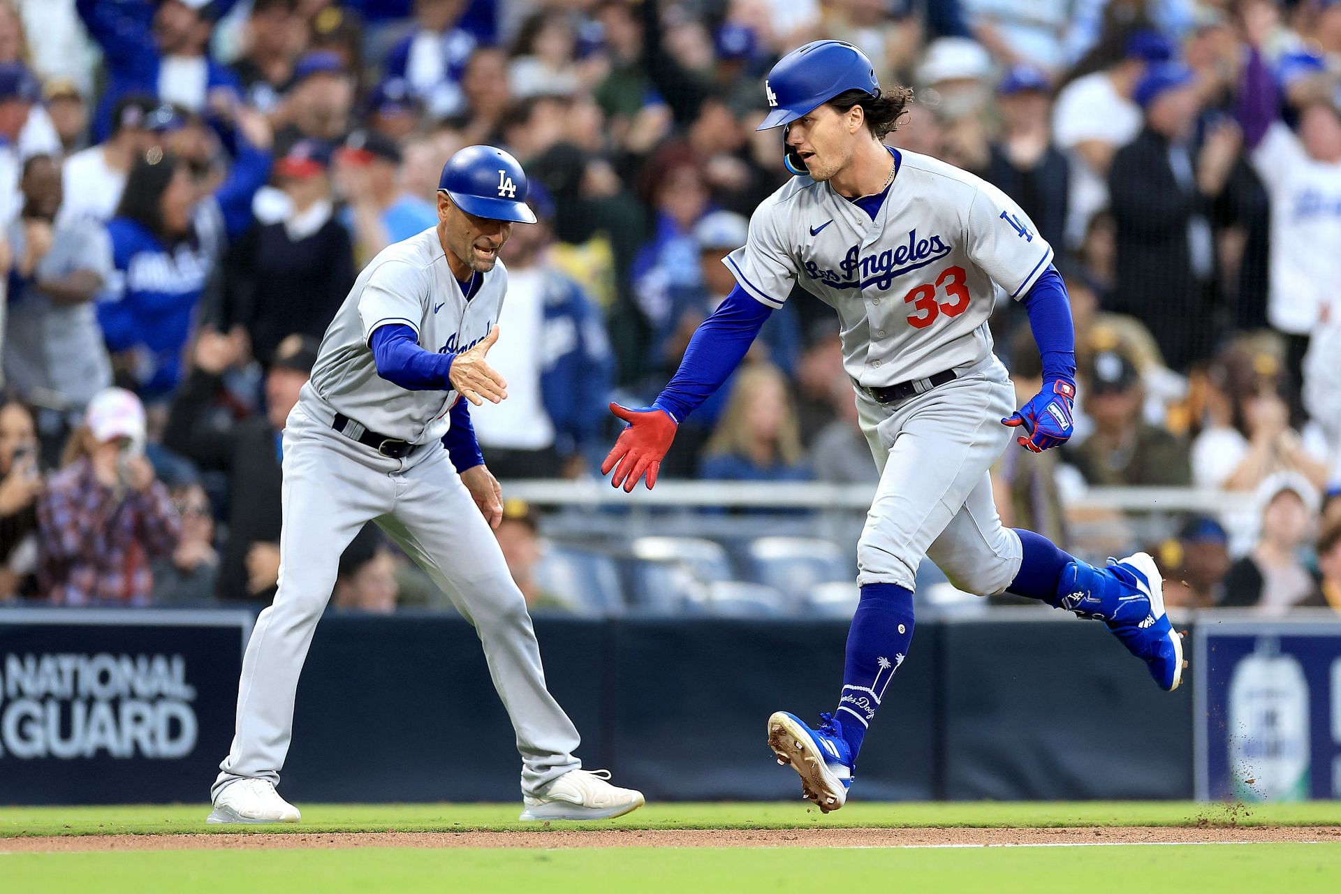 Third base coach Dino Ebel #91 celebrates as James Outman #33 of the Los Angeles Dodgers rounds third base after hitting a two-run homerun during the tenth inning of a game against the San Diego Padres