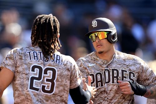 Fernando Tatis Jr. congratulates Manny Machado after he scores against the Los Angeles Dodgers at PETCO Park