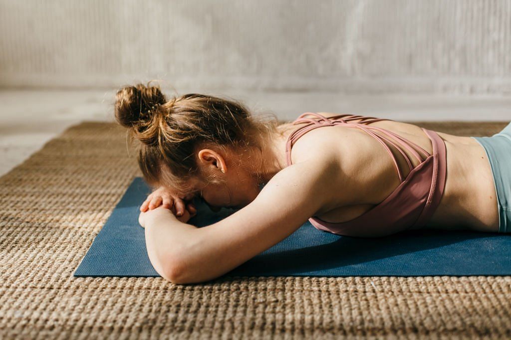 Close up young woman practicing yoga in yoga class on exercise mat(Image via Getty Images)