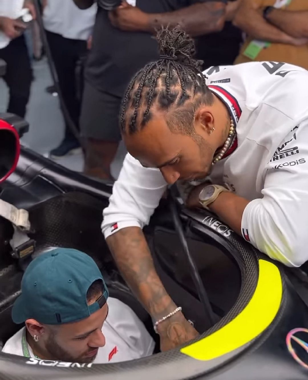 Lewis Hamilton assisting Neymar Jr to have a seat in his Mercedes W14