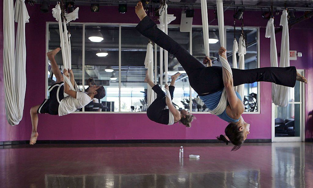 Dylan Giordano, from left, Shari Portnoy, and instructor Robin Retherford participate in a flip during an Antigravity Yoga with Wings class at Crunch Fitness