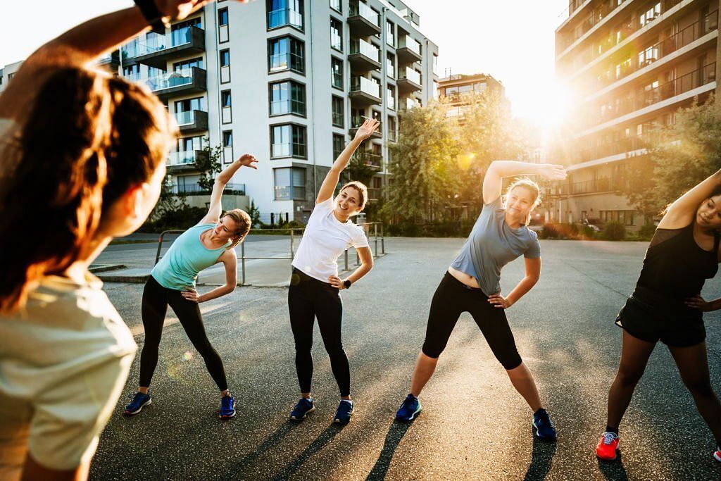 An urban fitness group for women warming up before a run through the city together(Image via Getty Images)
