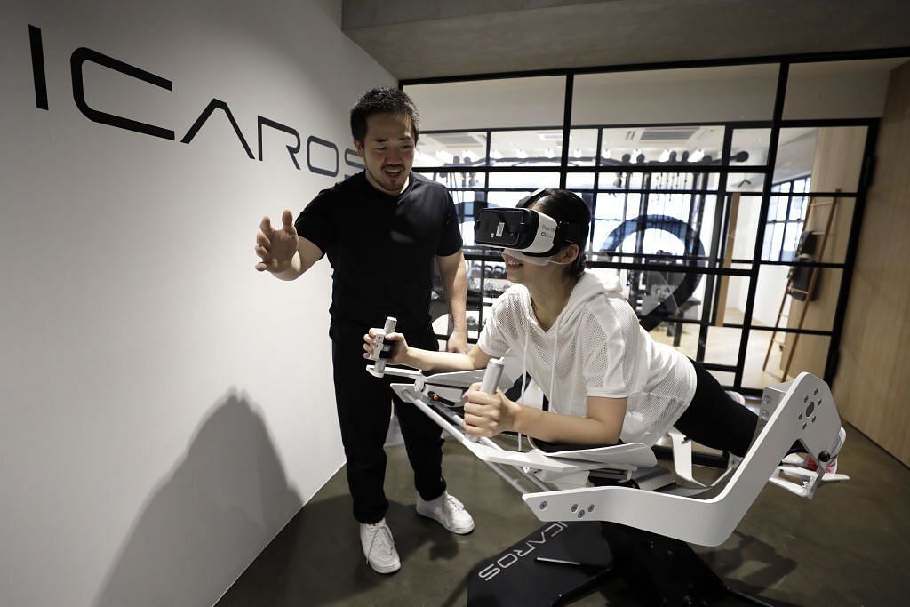 Shuhei Miyajima, a personal trainer, left, explains the use of the Icaros VR fitness machine(Image via Getty Images)