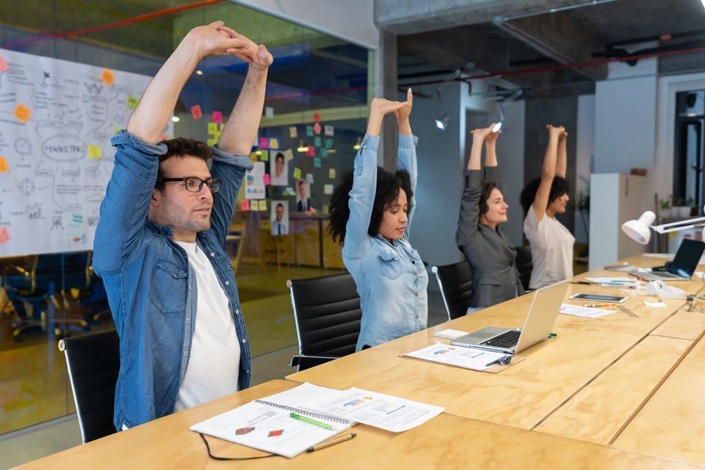 Workers doing stretching exercises at the office (Image via Getty Images)