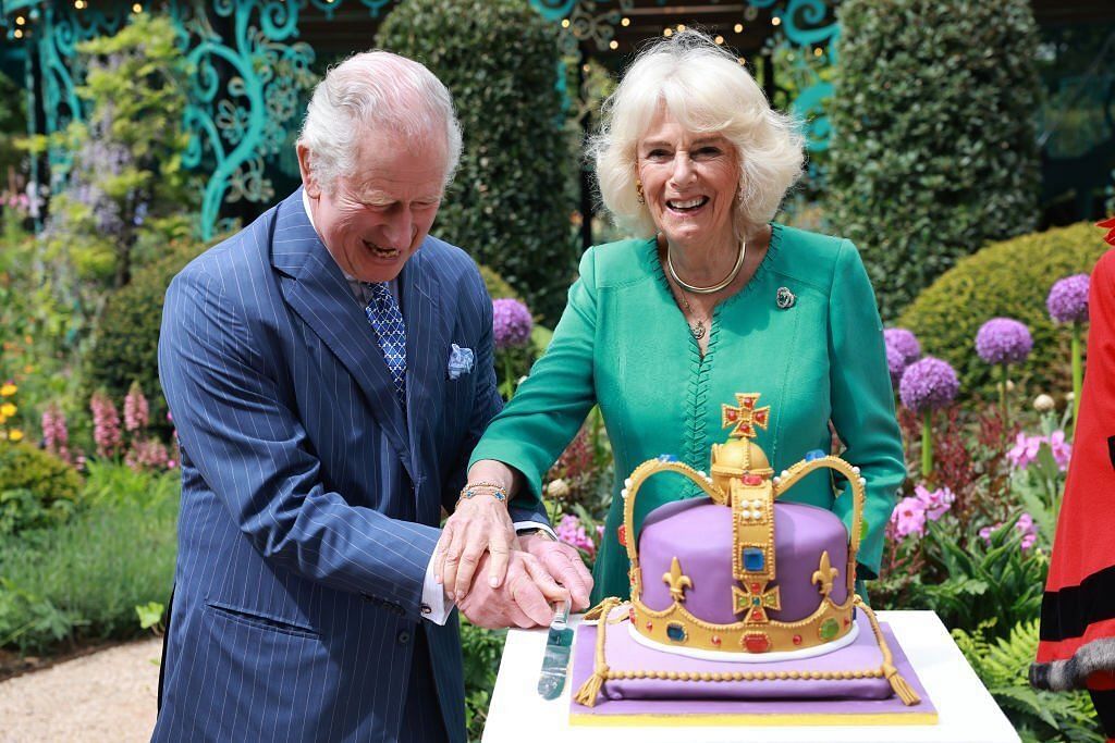 King Charles III and Queen Camilla laugh as they cut a cake during a visit to open the new Coronation Garden on day one of their two-day visit to Northern Ireland