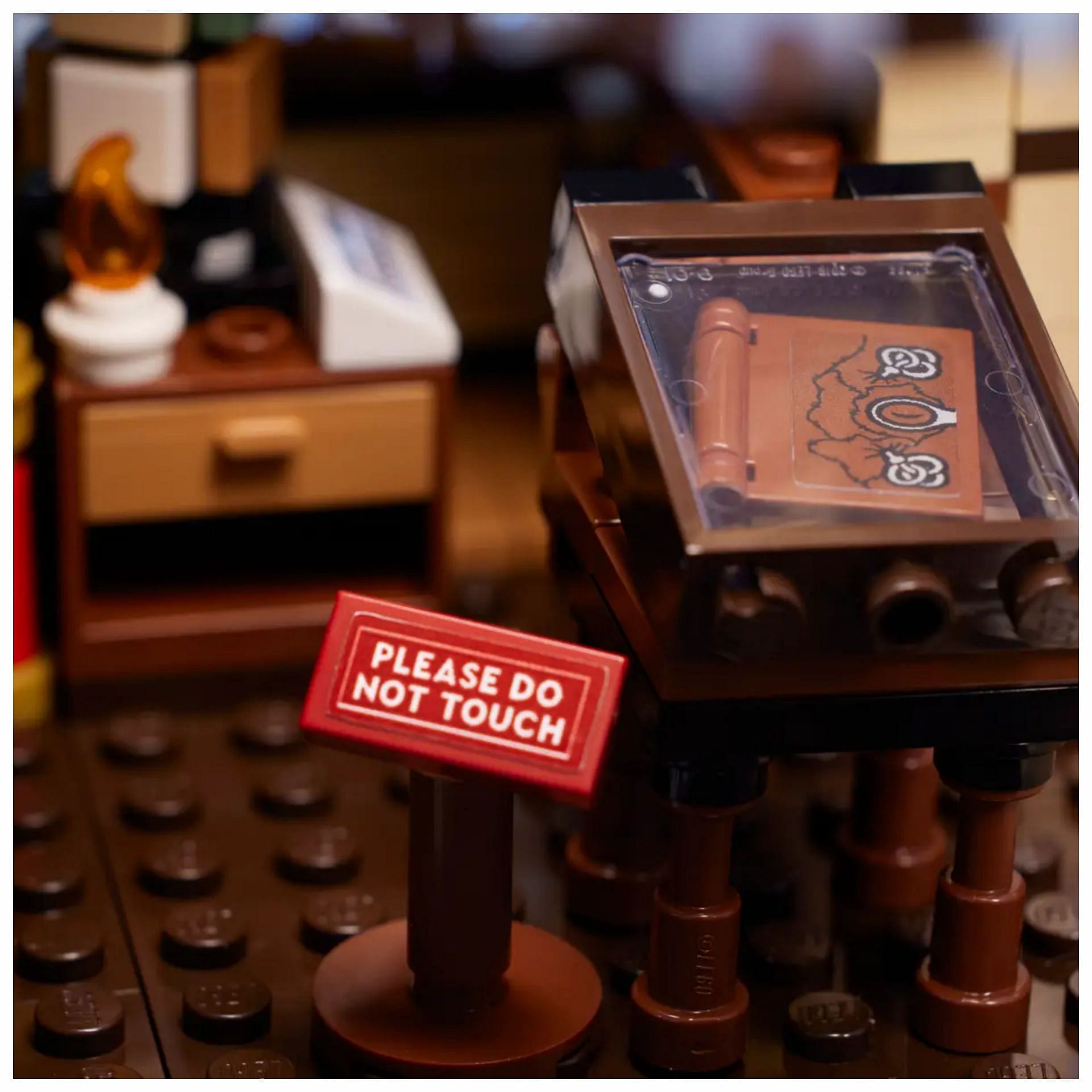 The infamous spellbook, protected by a glass case and a &quot;please do not touch&quot; sign (Image via lego.com)