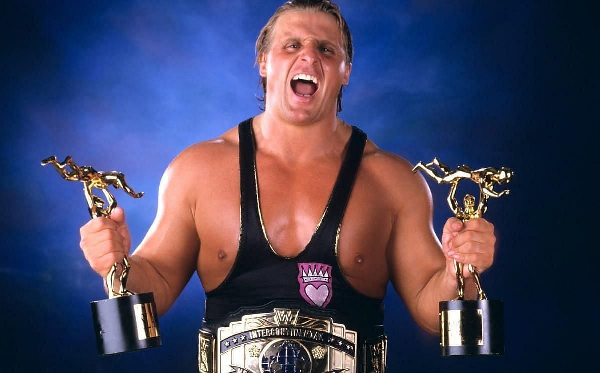 Owen Hart holding two Slammy Awards as WWE Intercontinental Champion.
