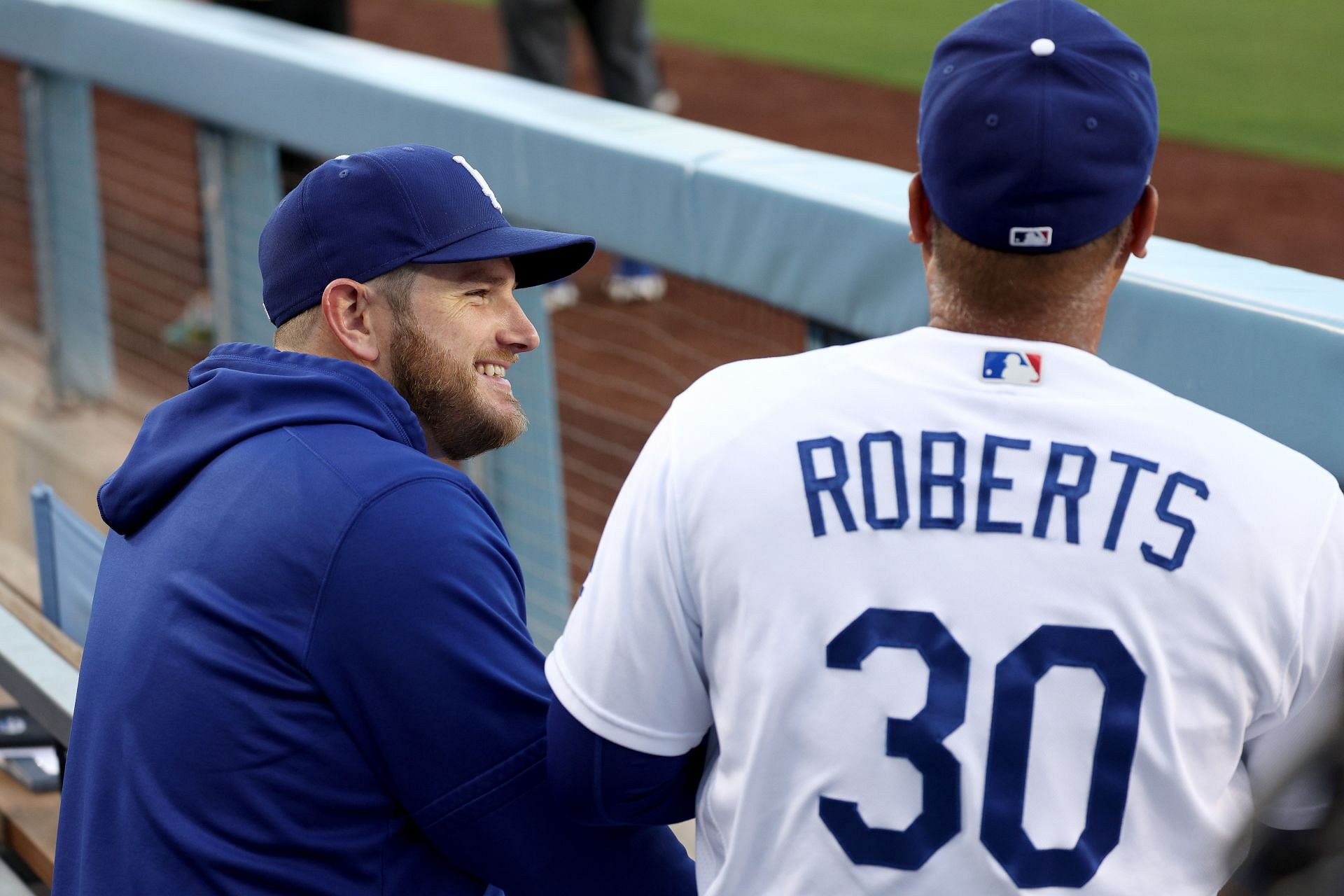 Max Muncy of the Los Angeles Dodgers smiles as he walks with Manager Dave Roberts at Dodger Stadium