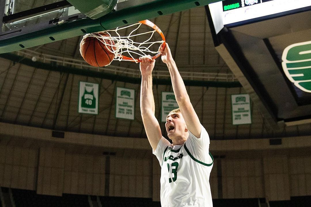 AJ Clayton dunks the basketball with two hands and hangs on the rim for a second. Via Instagram