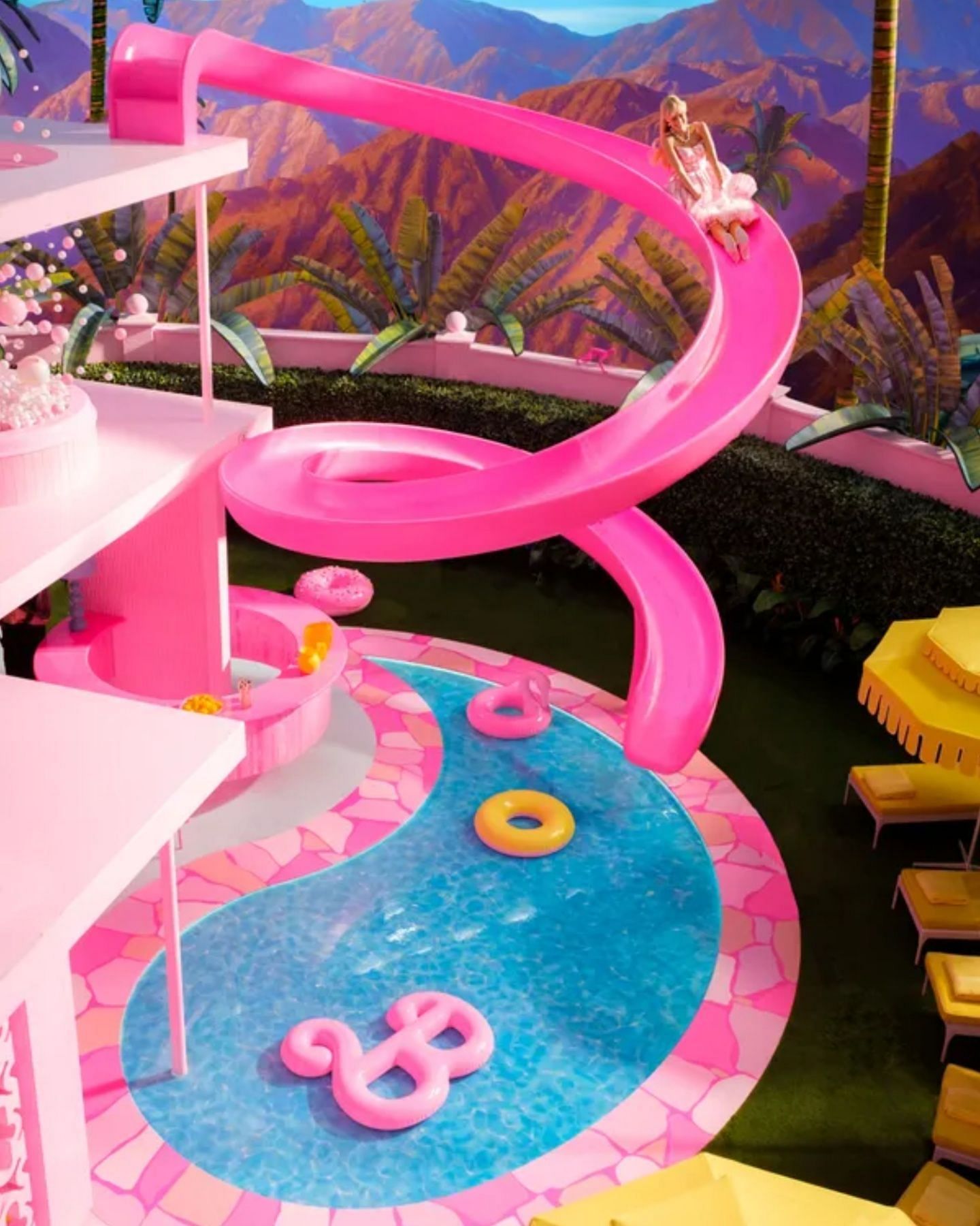 Margot Robbie descends the life-size slide in her Dreamhouse. (Image via Warner Bros. Pictures)