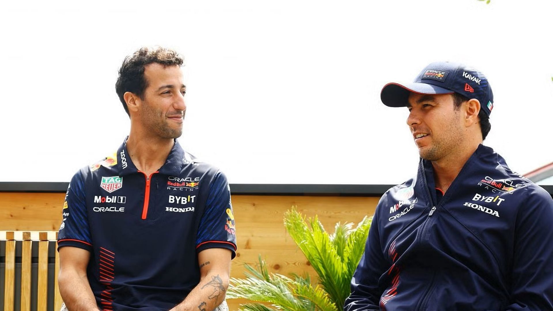 Daniel Ricciardo and Sergio Perez talk in the paddock during previews ahead of the 2023 F1 British Grand Prix. (Photo by Mark Thompson/Getty Images)