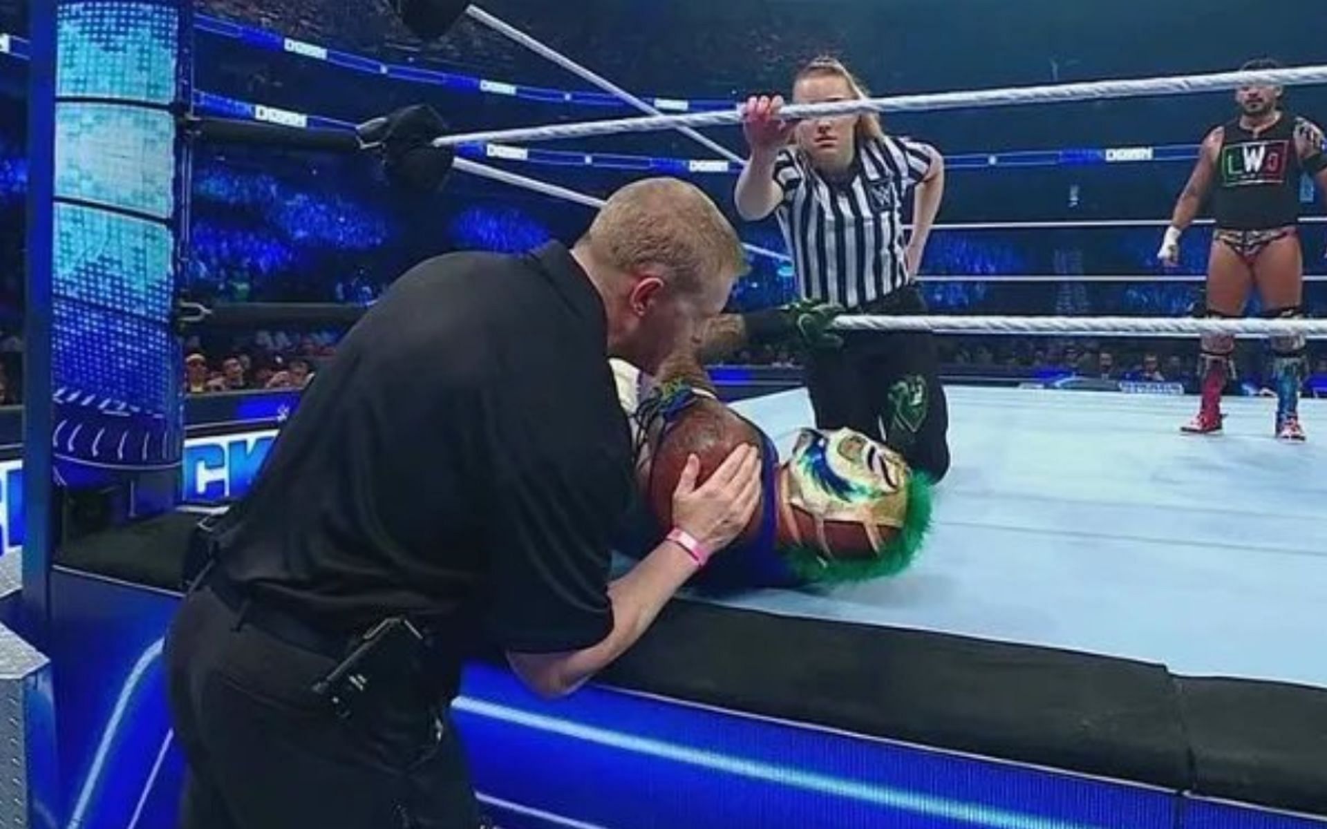 A medical official checking up on Rey Mysterio during his match