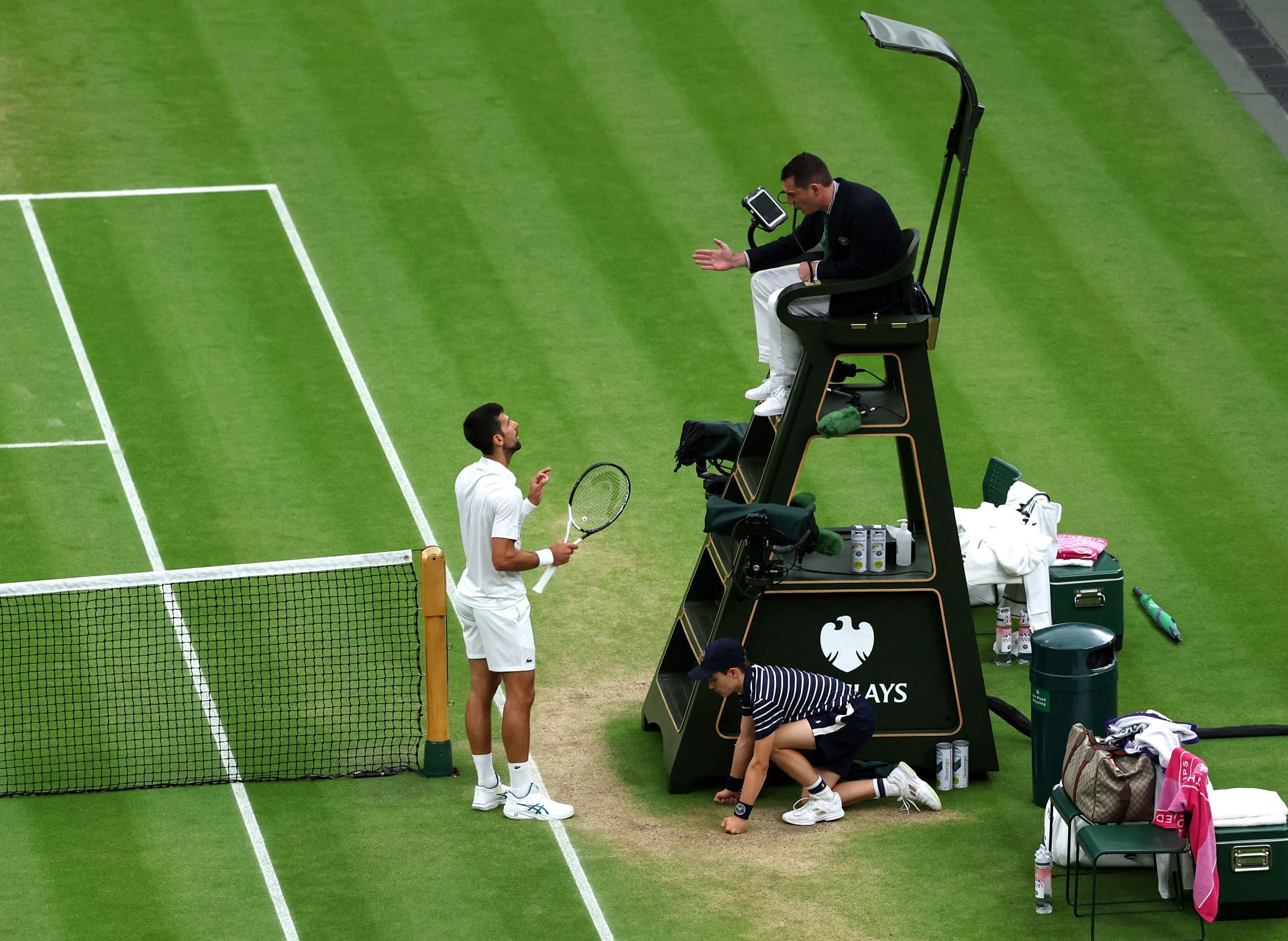 Novak Djokovic talks with chair umpire Richard Haigh after losing a point for hindrance.