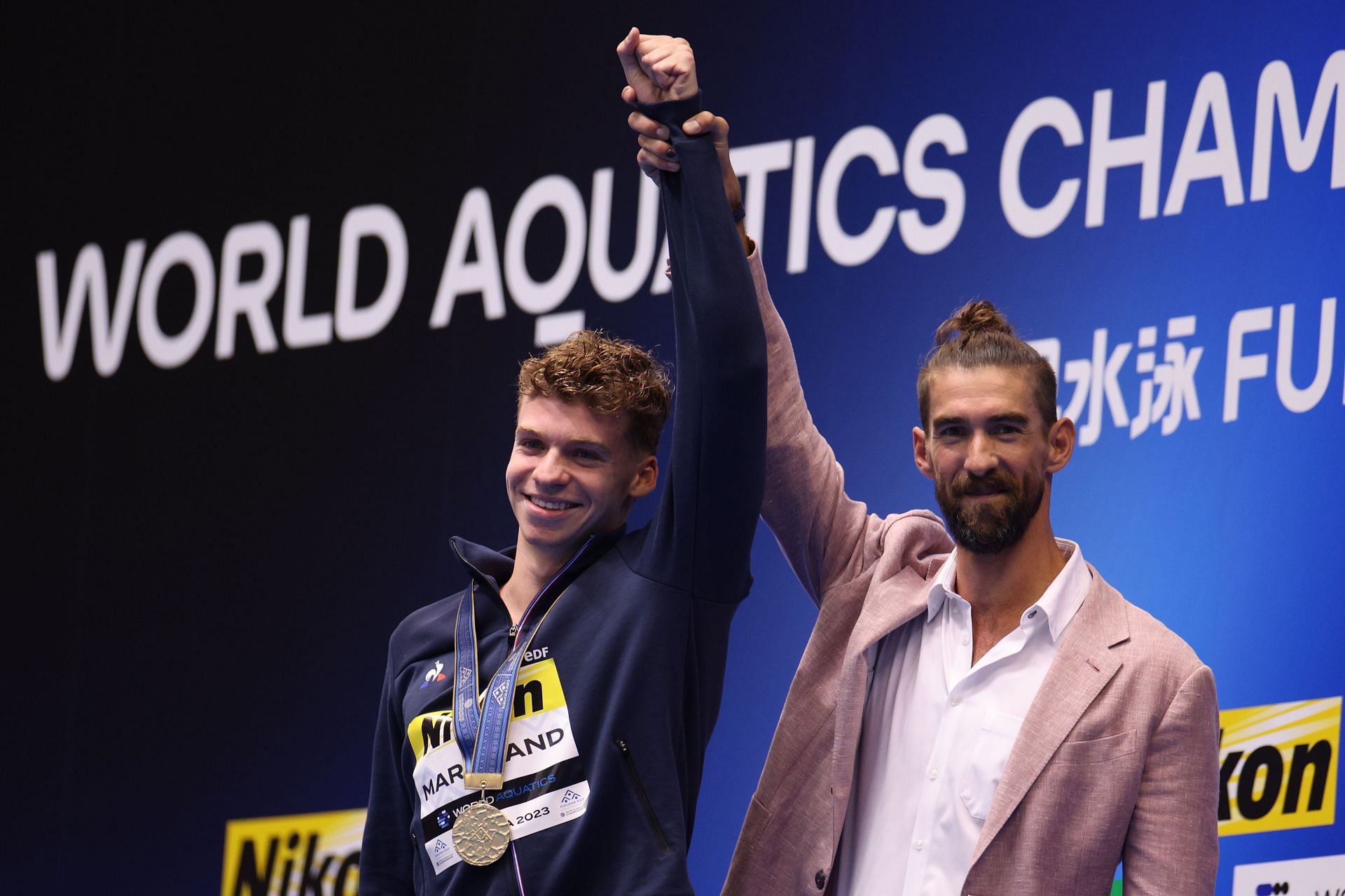 Michael Phelps congratulates Leon Marchand during the medal ceremony of men's 400m IM at Fukuoka 2023 World Aquatics Championships in Japan