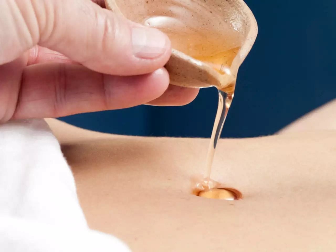 Castor oil on belly button (Image via Getty Images)