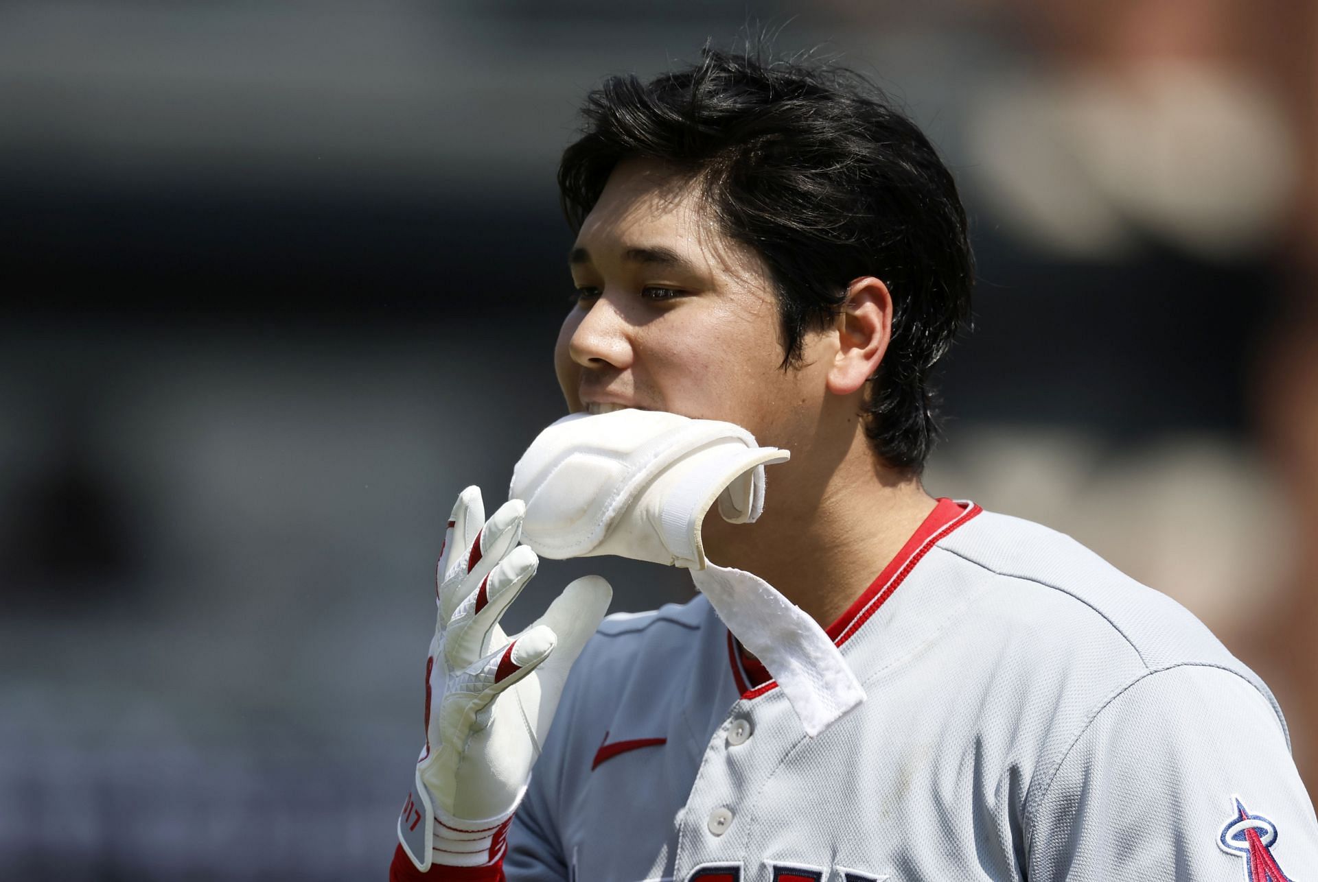 Shohei Ohtani of the Los Angeles Angels holds his protecting gear in his mouth at Comerica Park