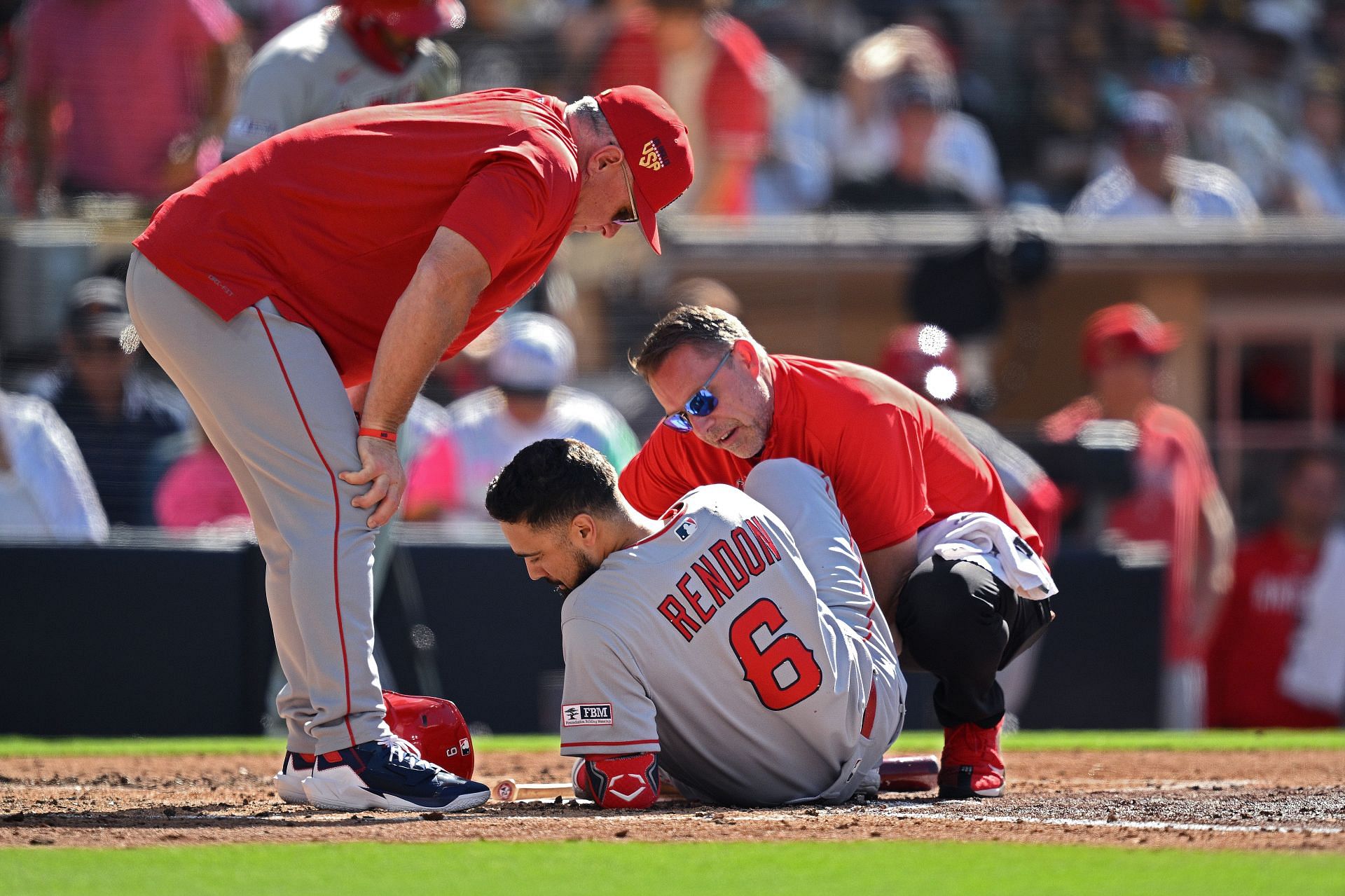 Anthony Rendon of the Los Angeles Angels lays on the field while being checked by a trainer.