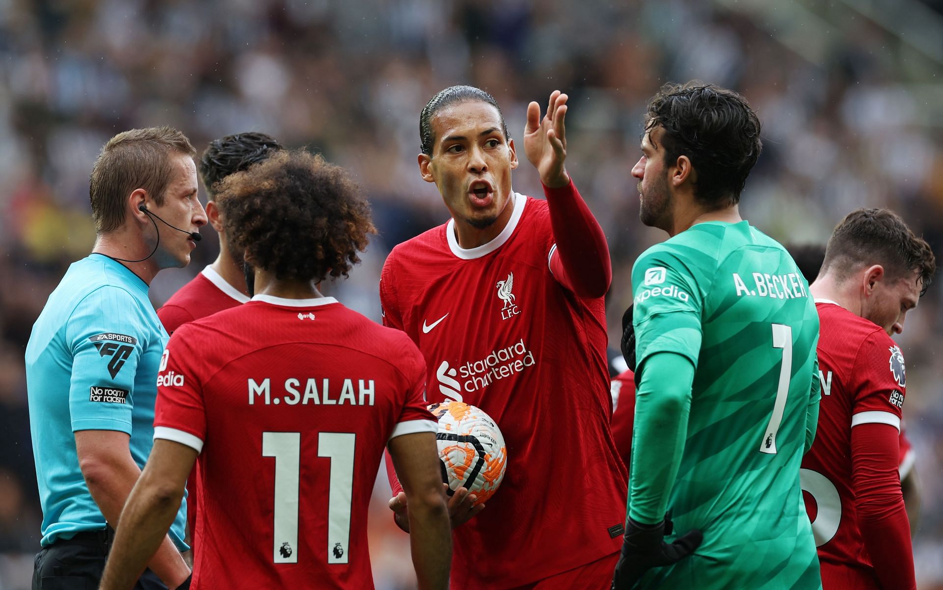 Liverpool captain Virgil van Dijk in conversation with the referee after a red card decision.