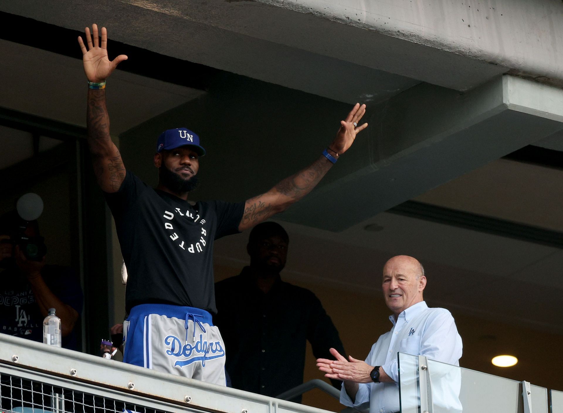 LeBron James of the LA Lakers waves in front of President and CEO of the Los Angeles Dodgers, Stan Kasten, at Dodger Stadium.