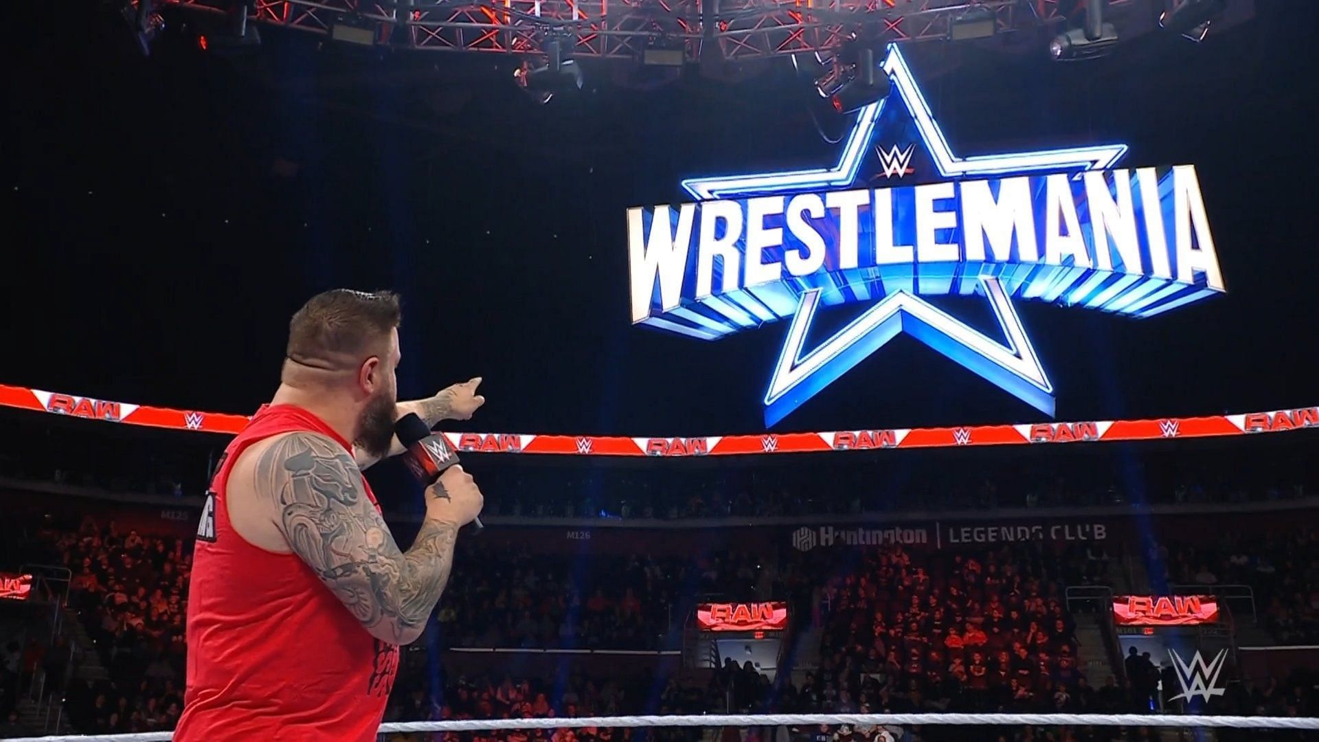 Kevin Owens pointing at the WrestleMania 38 sign.