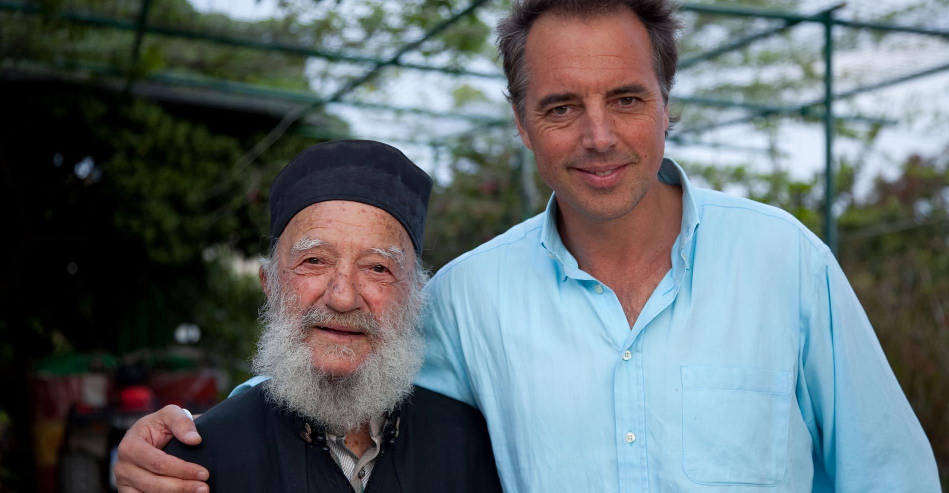 Host of the upcoming Netflix docu-series Dan Buettner with a Blue Zone community member in Ikaria, Greece (image via Bluezones.com)