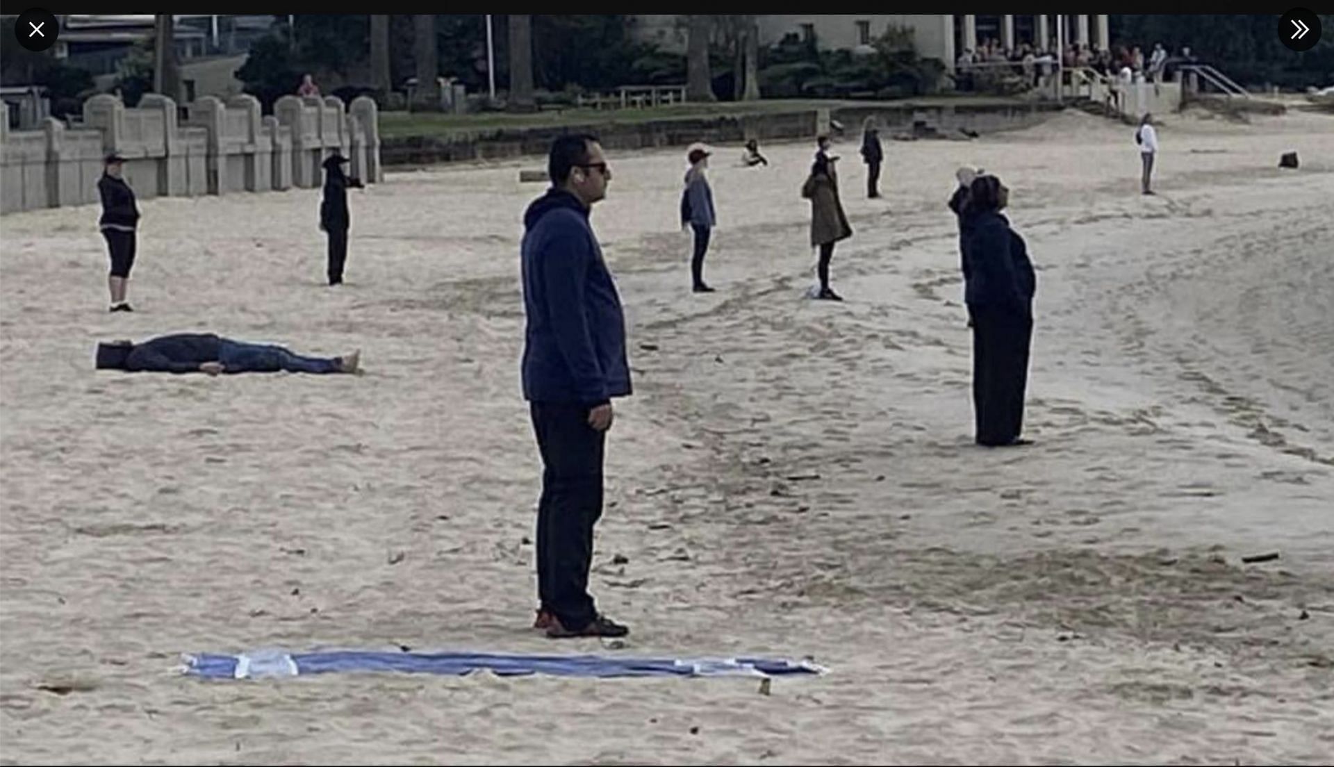 Social media users left stunned as a picture of people standing still staring at the sea in Sydney goes viral. (Image via Twitter)