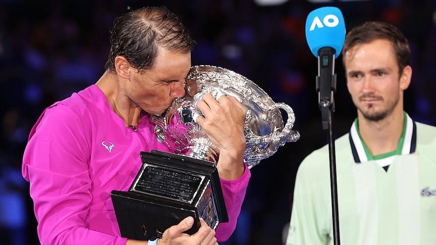 Rafael Nadal kisses the Australian Open winner&#039;s trophy as runner-up Daniil Medvedev looks on