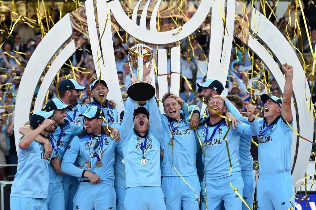 Joe Root celebrates in the background as Eoin Morgan lifts the 2019 World Cup trophy. (Credits: Twitter)