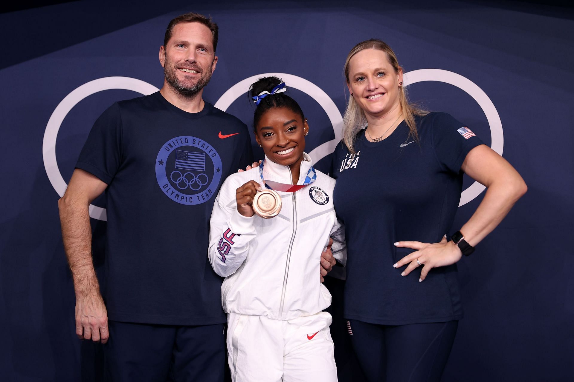 Simone Biles poses with the bronze medal alongside coaches Laurent Landi and Cecile Canqueteau-Landi following the Women's Balance Beam Final at the 2020 Tokyo Olympic Games in Tokyo, Japan.